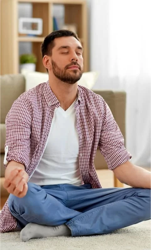 man meditating in lotus pose in living room