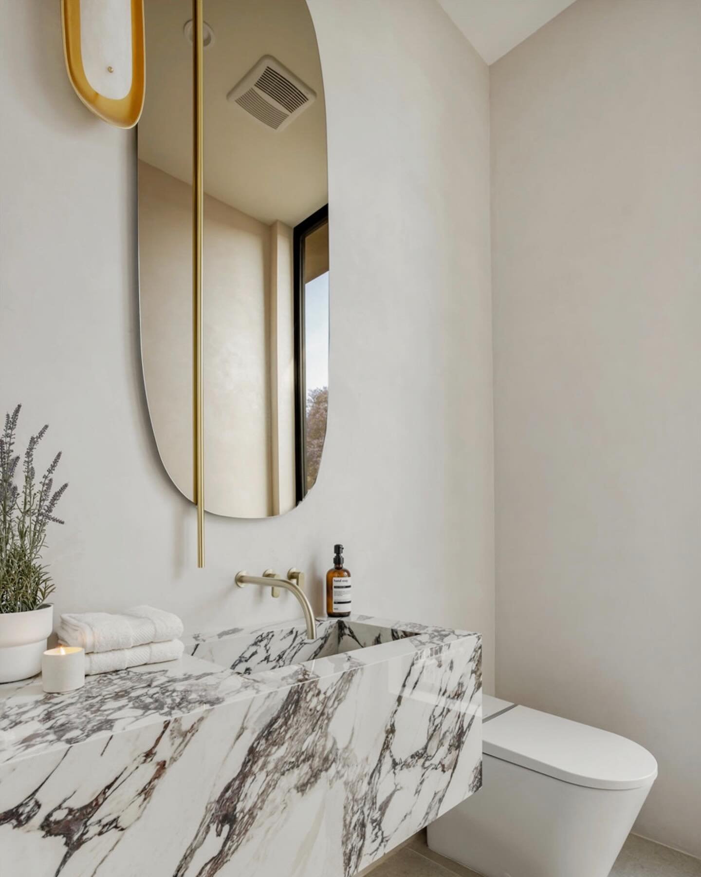 I really loved designing this powder room. Asymmetrical smoked glass mirror and sconce, plaster walls, Calacatta Viola integrated sink, and sleek European faucet by @cocoonbathroom make it so special. 🩶

Designed by me 😊