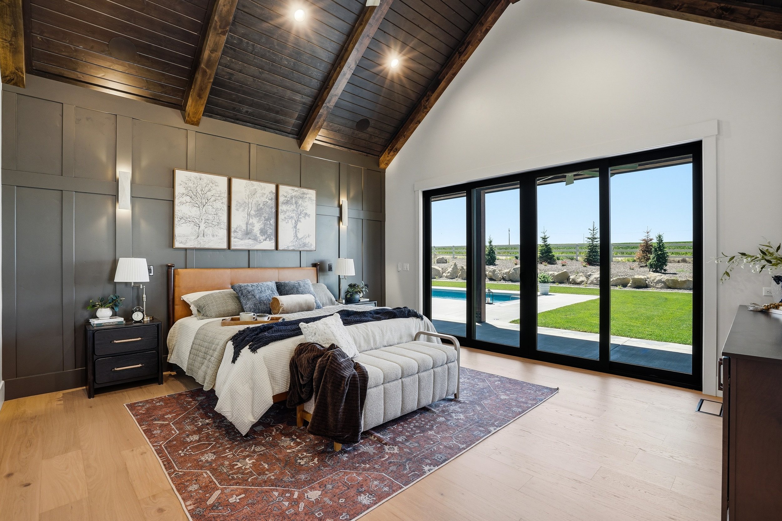 Award-winning primary suite in The Cody by Bachman Custom Homes featuring a vaulted wood-beam ceiling and paneled accent wall, staged by LD Luxury Design and Staging.