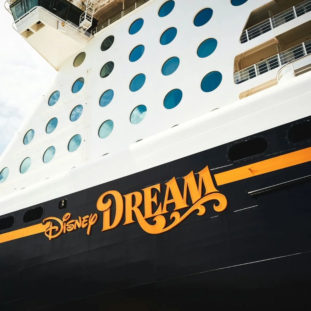 Close-up of the Disney Dream cruise ship with its name displayed in orange letters on the hull.