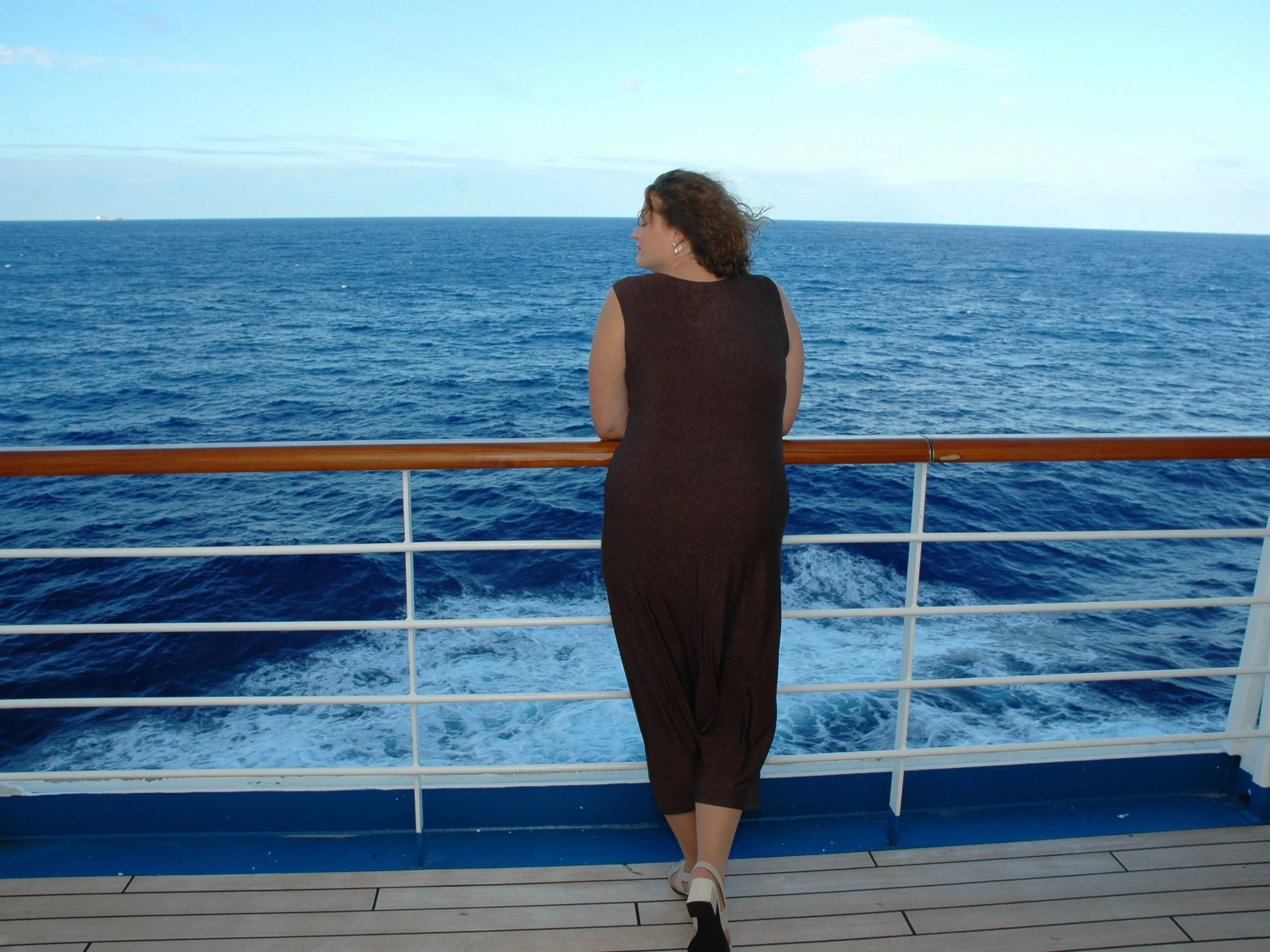 Person relaxing on cruise ship railing with open ocean view