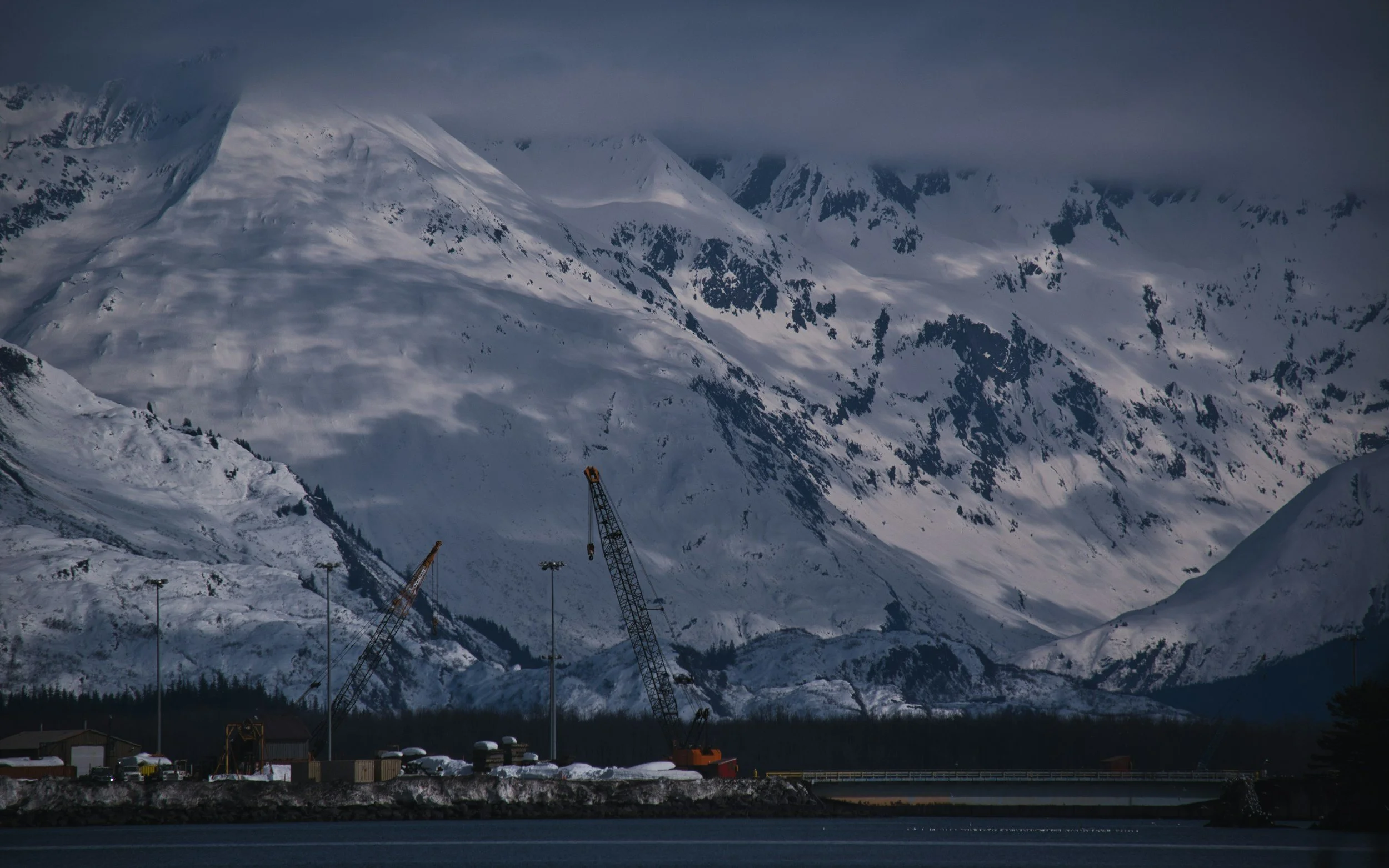Remote Alaska coastal town harbor surrounded by dramatic mountain scenery