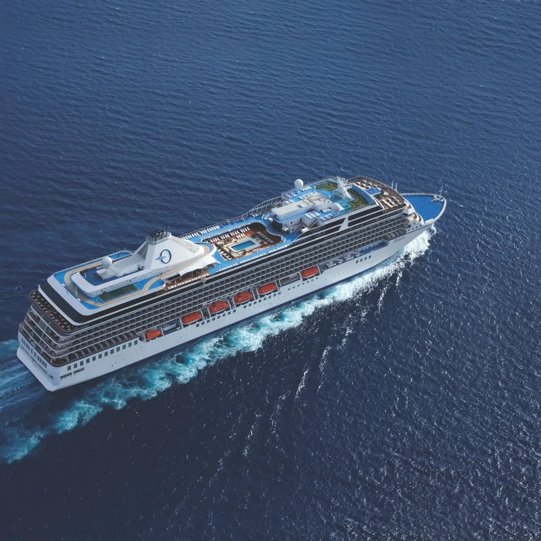 A large cruise ship sailing through the ocean with visible decks, pools, and leisure areas.