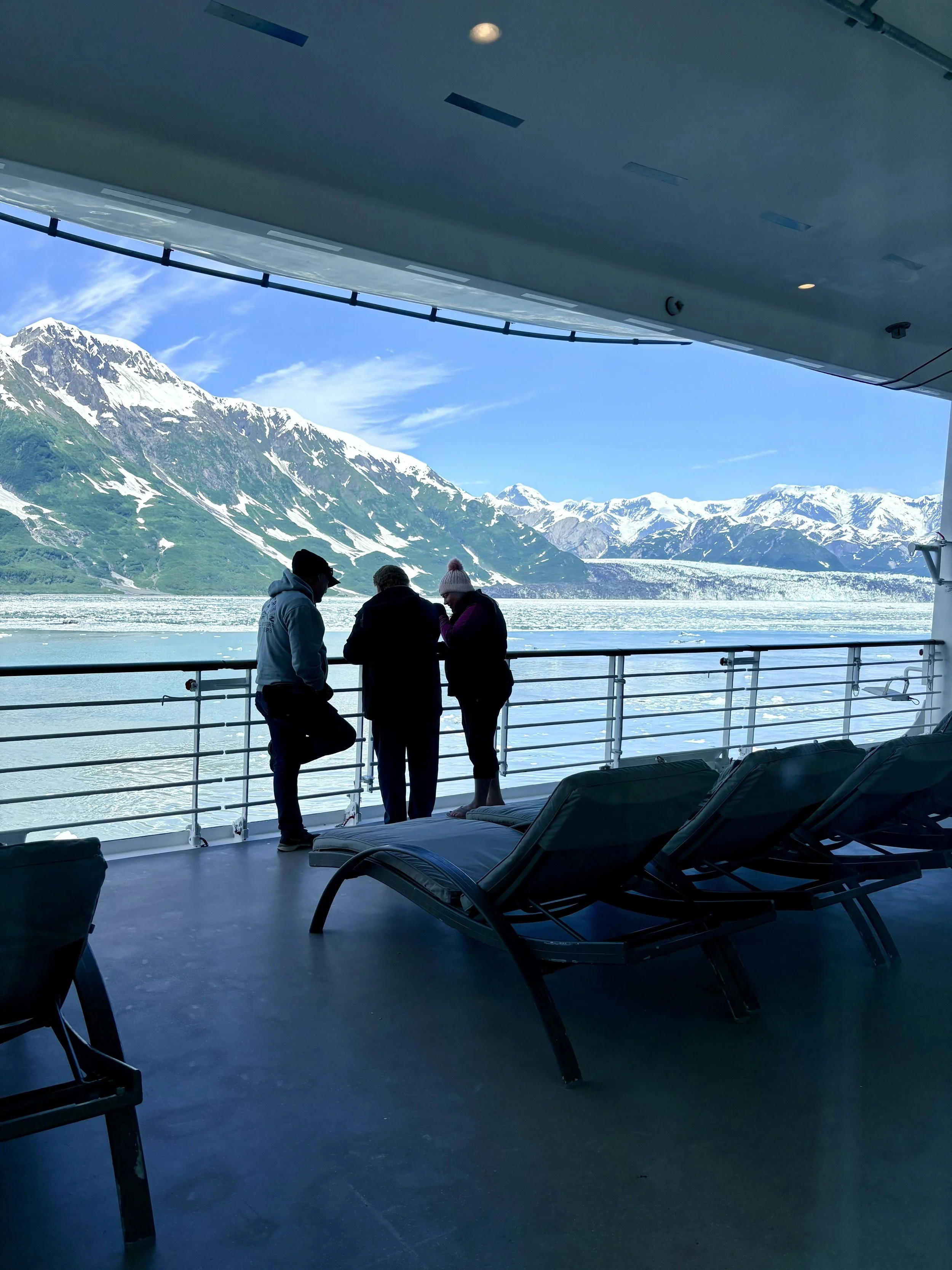 Travelers on cruise ship deck experiencing Hubbard Glacier Alaska with warm drinks in cold air