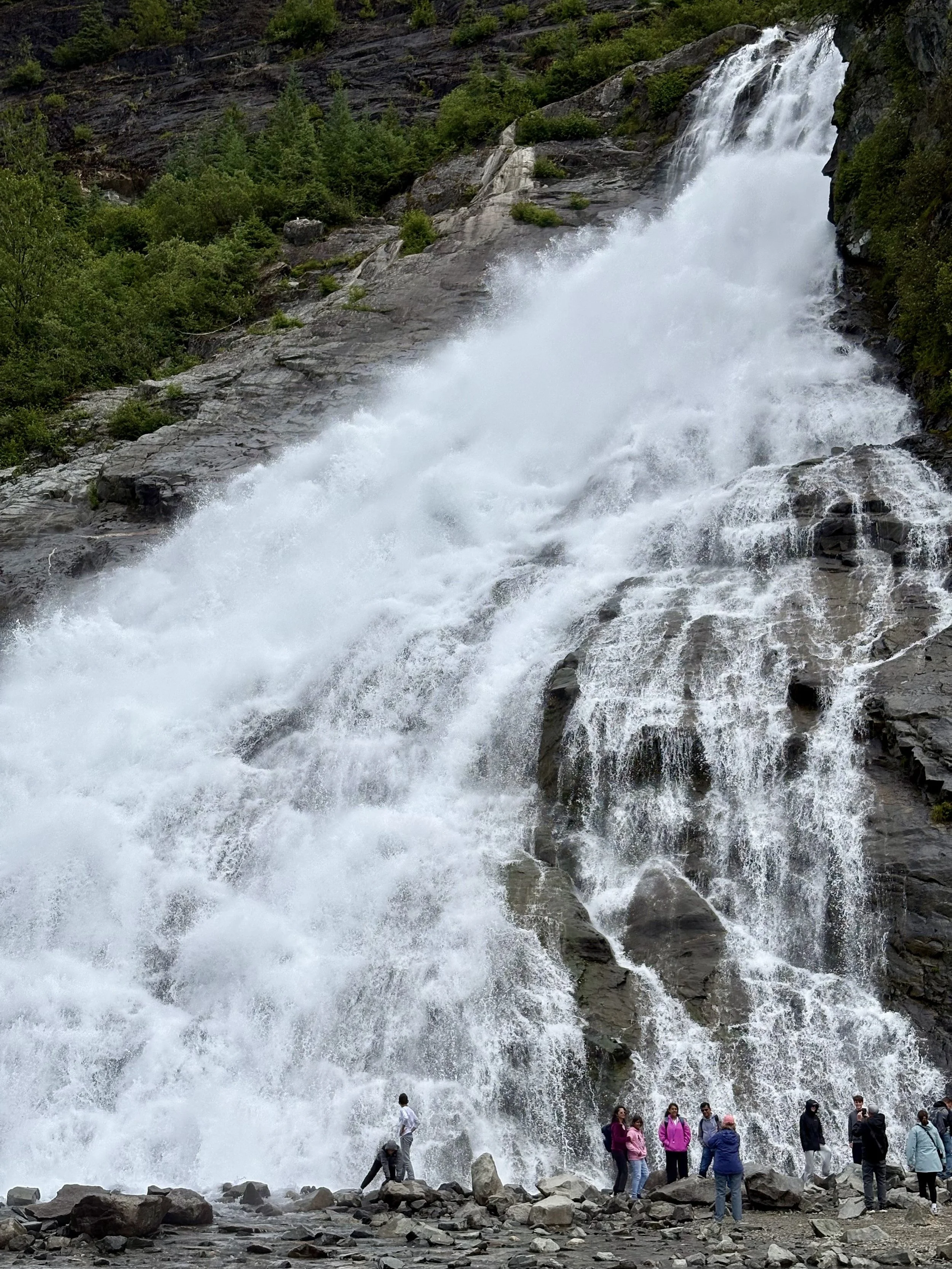 People posing in front of Nugget Falls, looking small in comparison