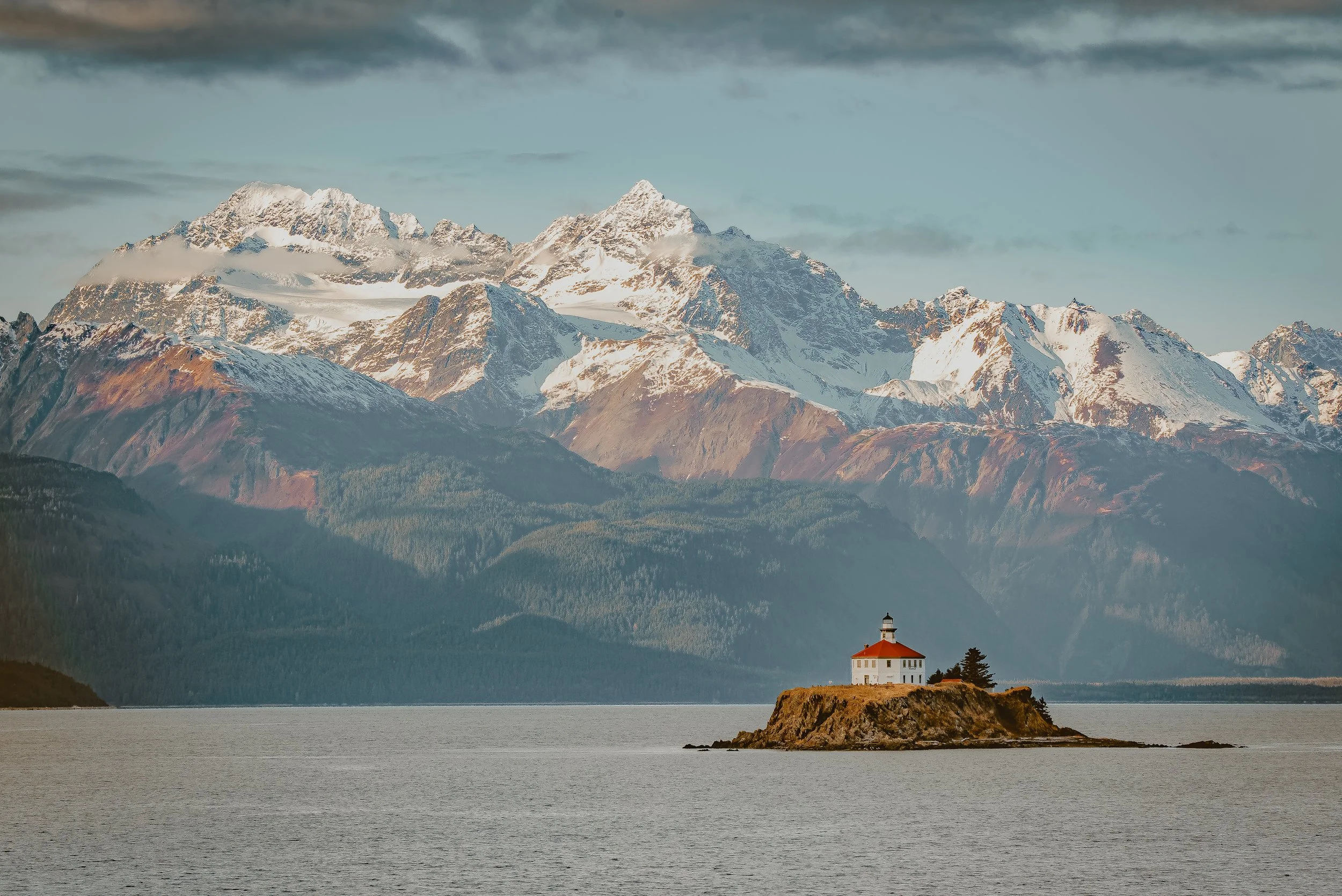 Quiet Alaska coastal village harbor with forested mountains in the background