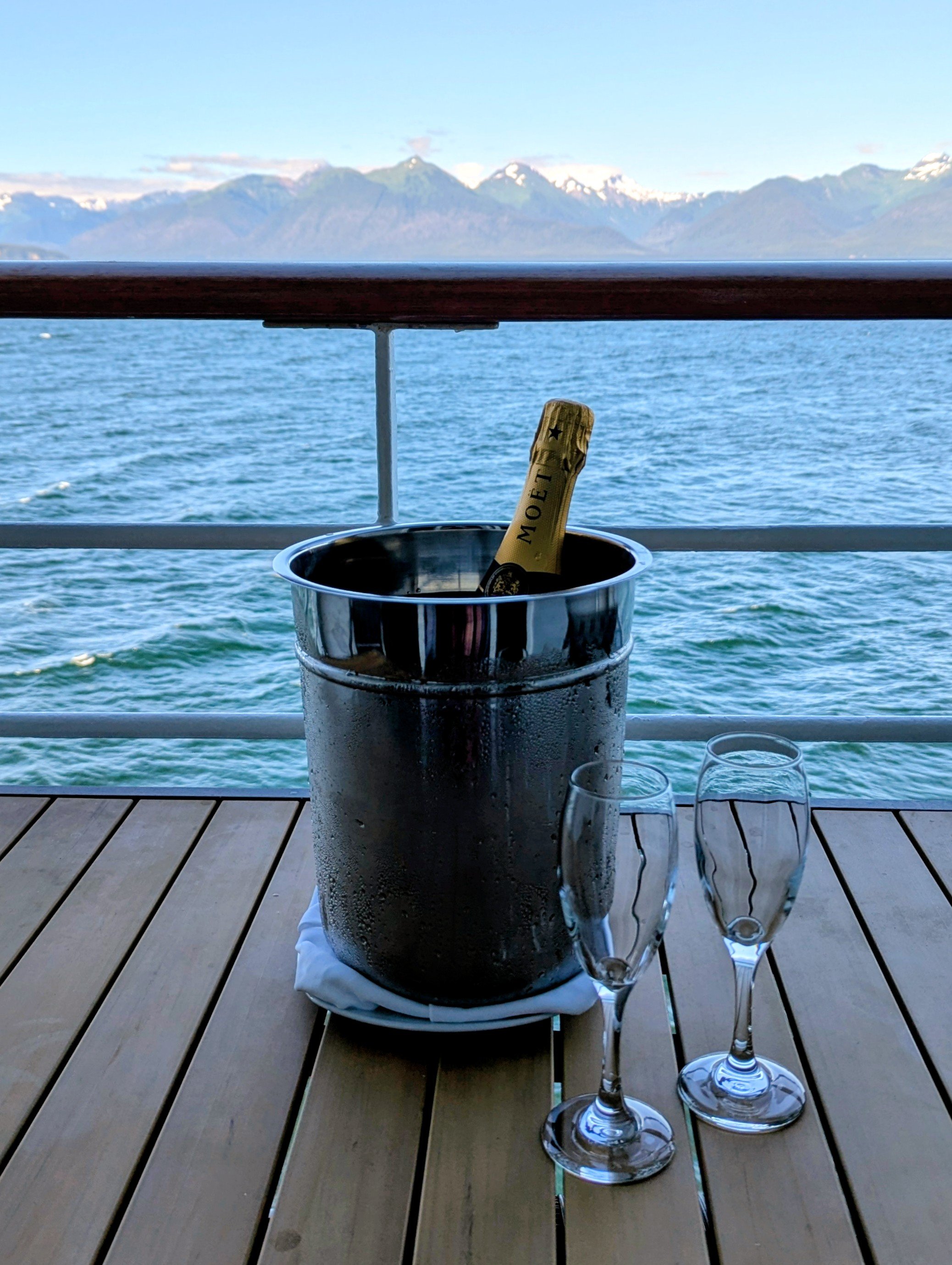 Bottle of champagne chilling on the veranda overlooking the mountains of the Inside Passage