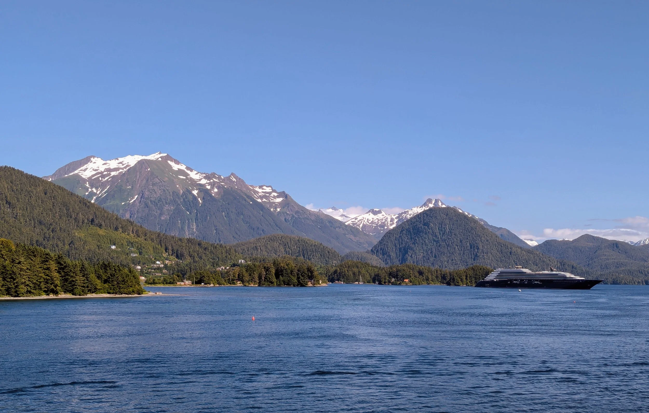 Small cruise ship sailing through dramatic Alaska Inside Passage with towering mountain scenery