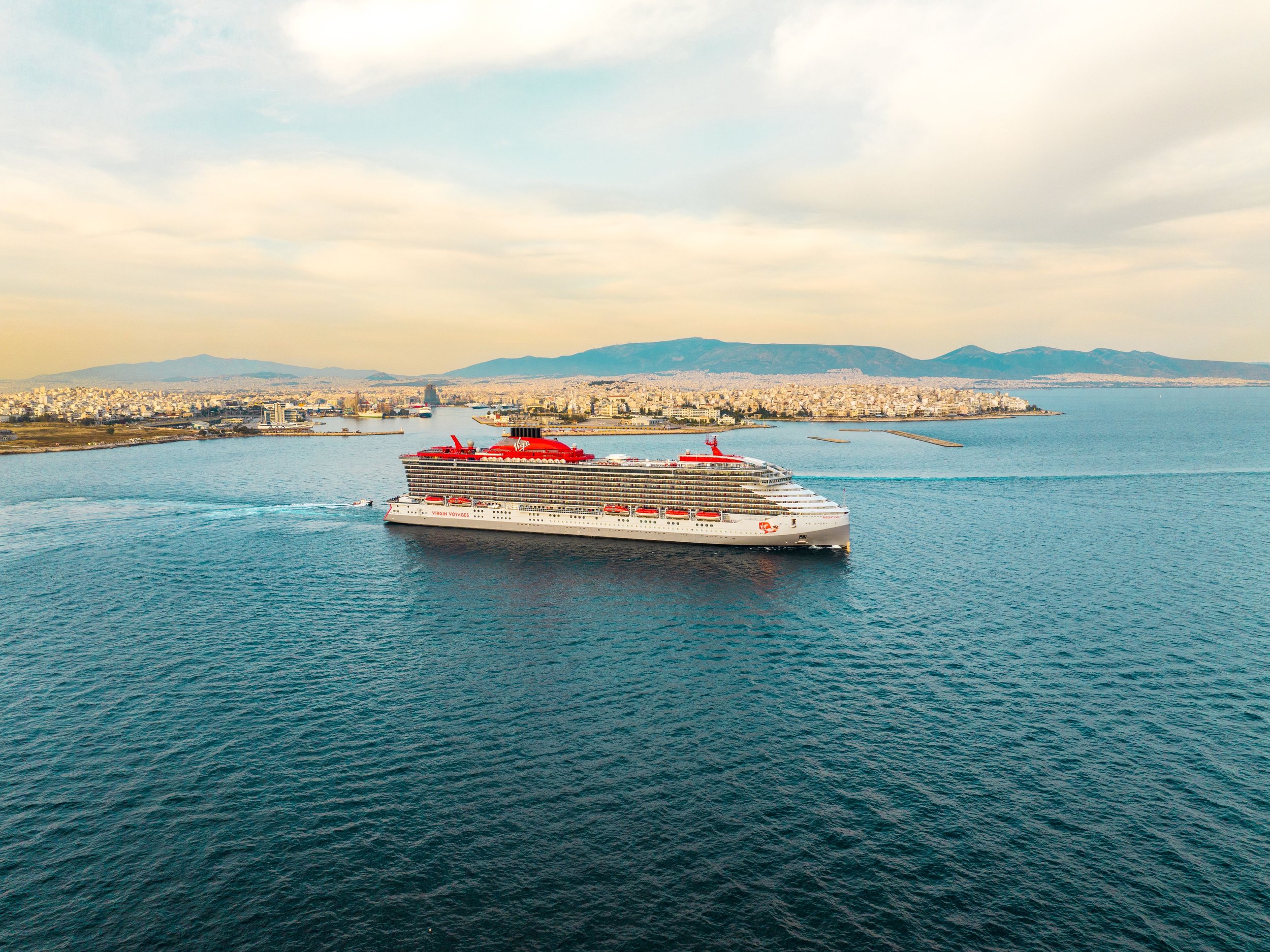 Luxury cruise ship sailing through blue Mediterranean waters past coastal cliffs
