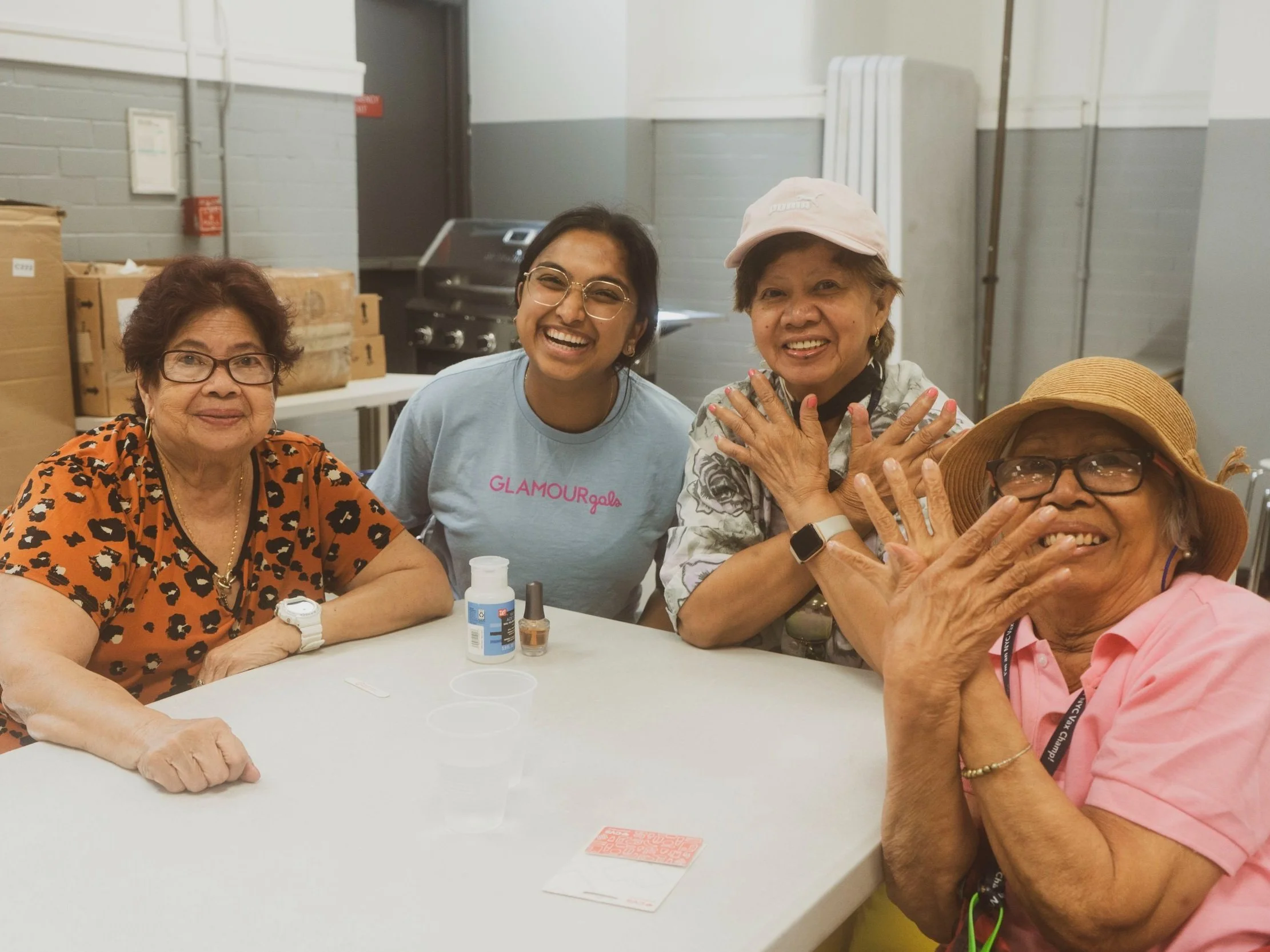 Four women sitting at a table, smiling and enjoying a social gathering.