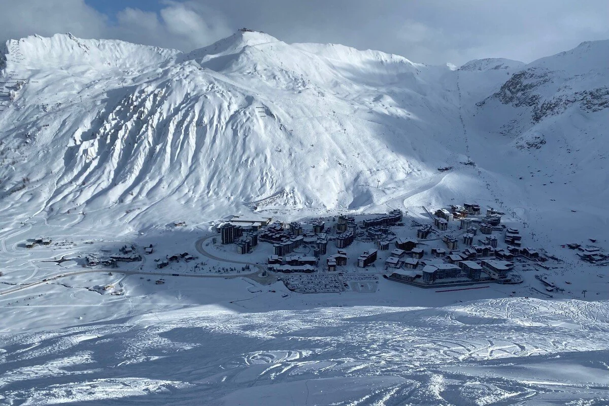 A snow-covered Tignes mountain landscape with a ski resort and buildings at the base.
