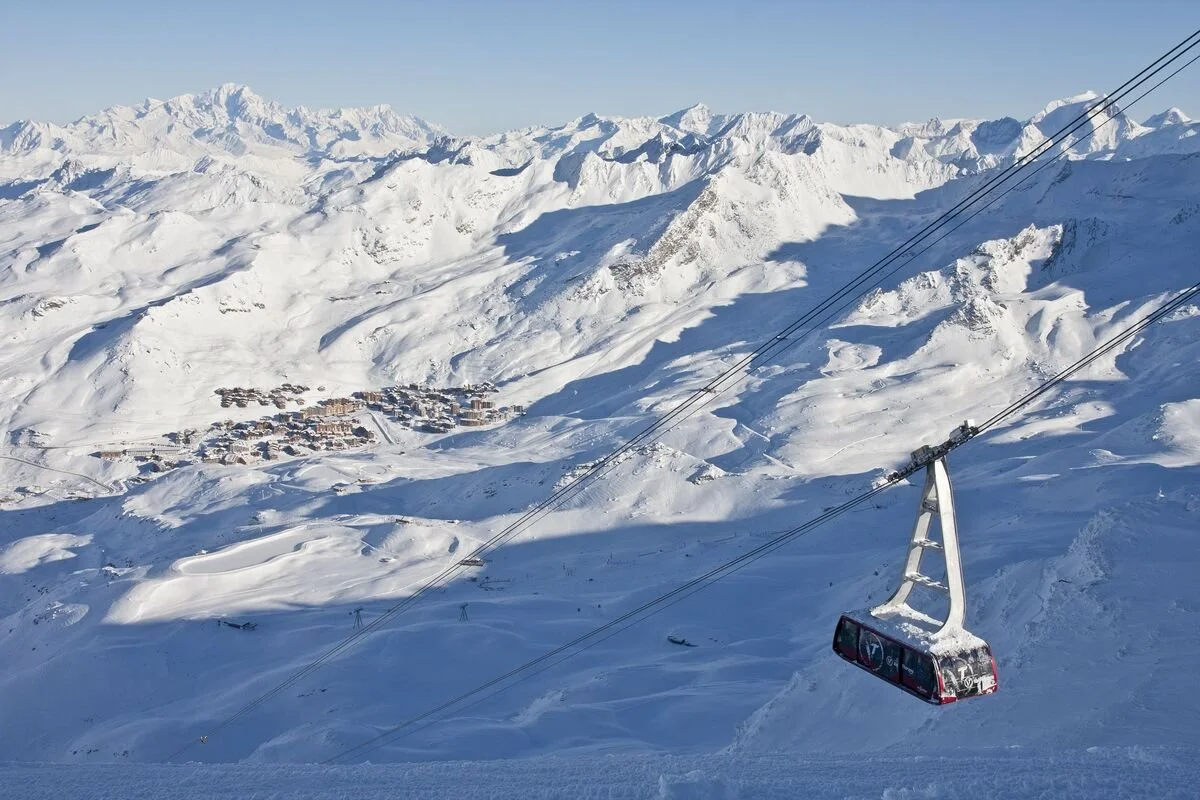 Snow-covered Val Thorens mountain landscape with a ski village and a ski lift in the foreground.
