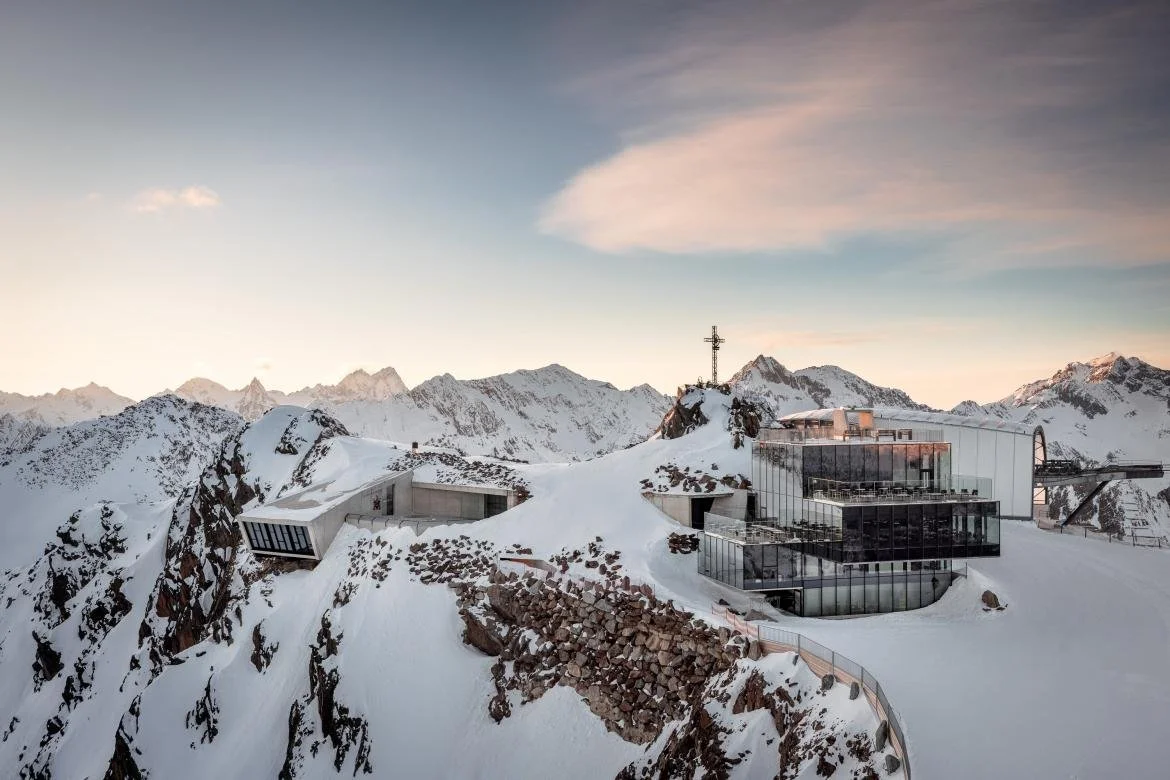 007 Elements building in Solden with glass windows on snowy mountain landscape during sunset or sunrise.