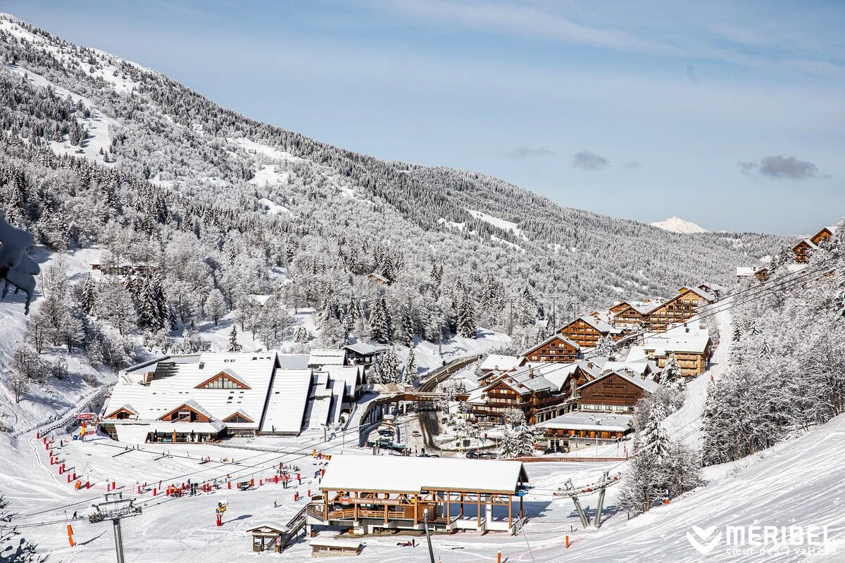 Meribel village in a snowy mountain landscape with snow-covered trees, chalets, and ski lifts
