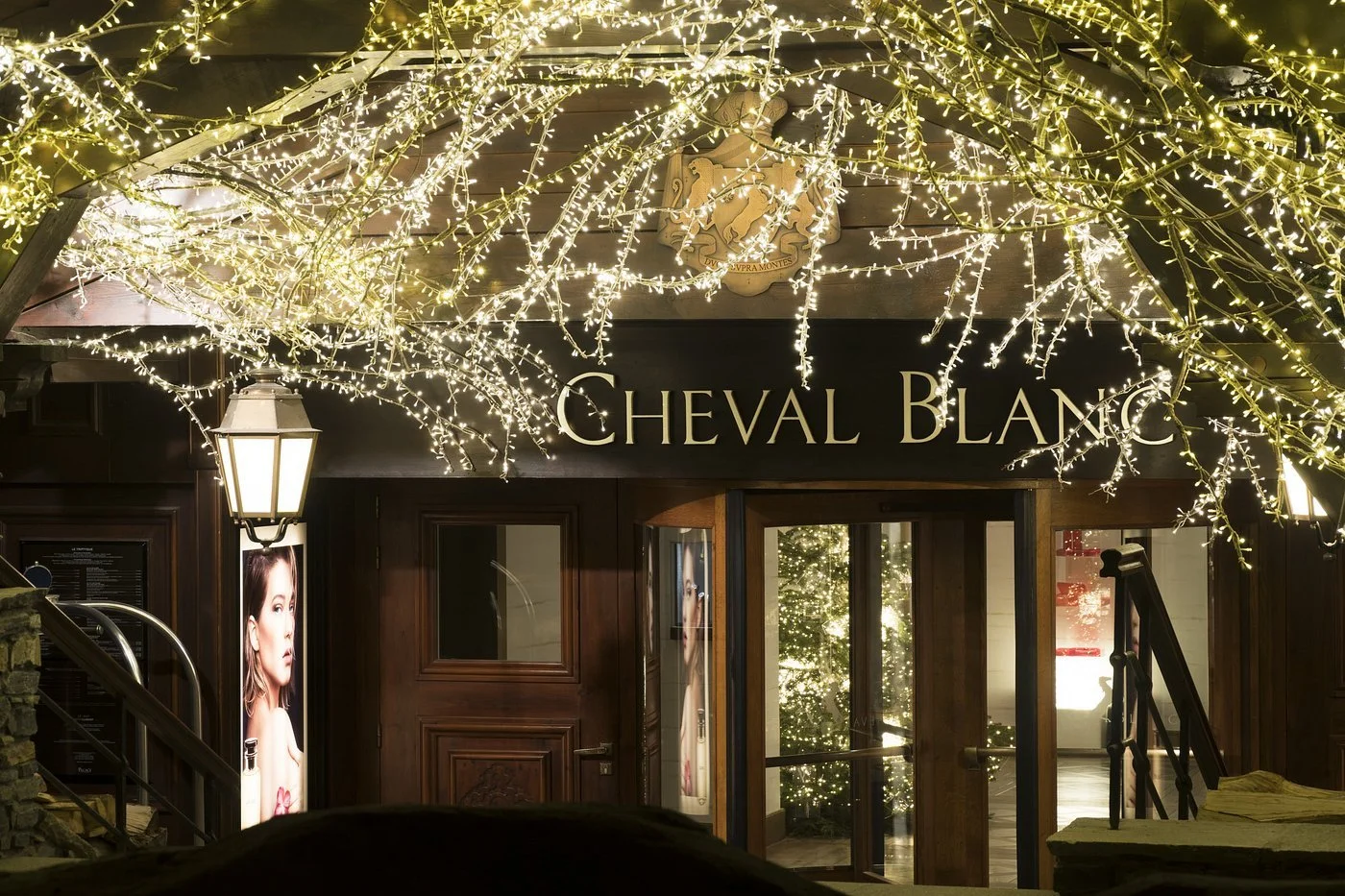 Entrance of Cheval Blanc decorated with Christmas lights and a Christmas tree visible inside.