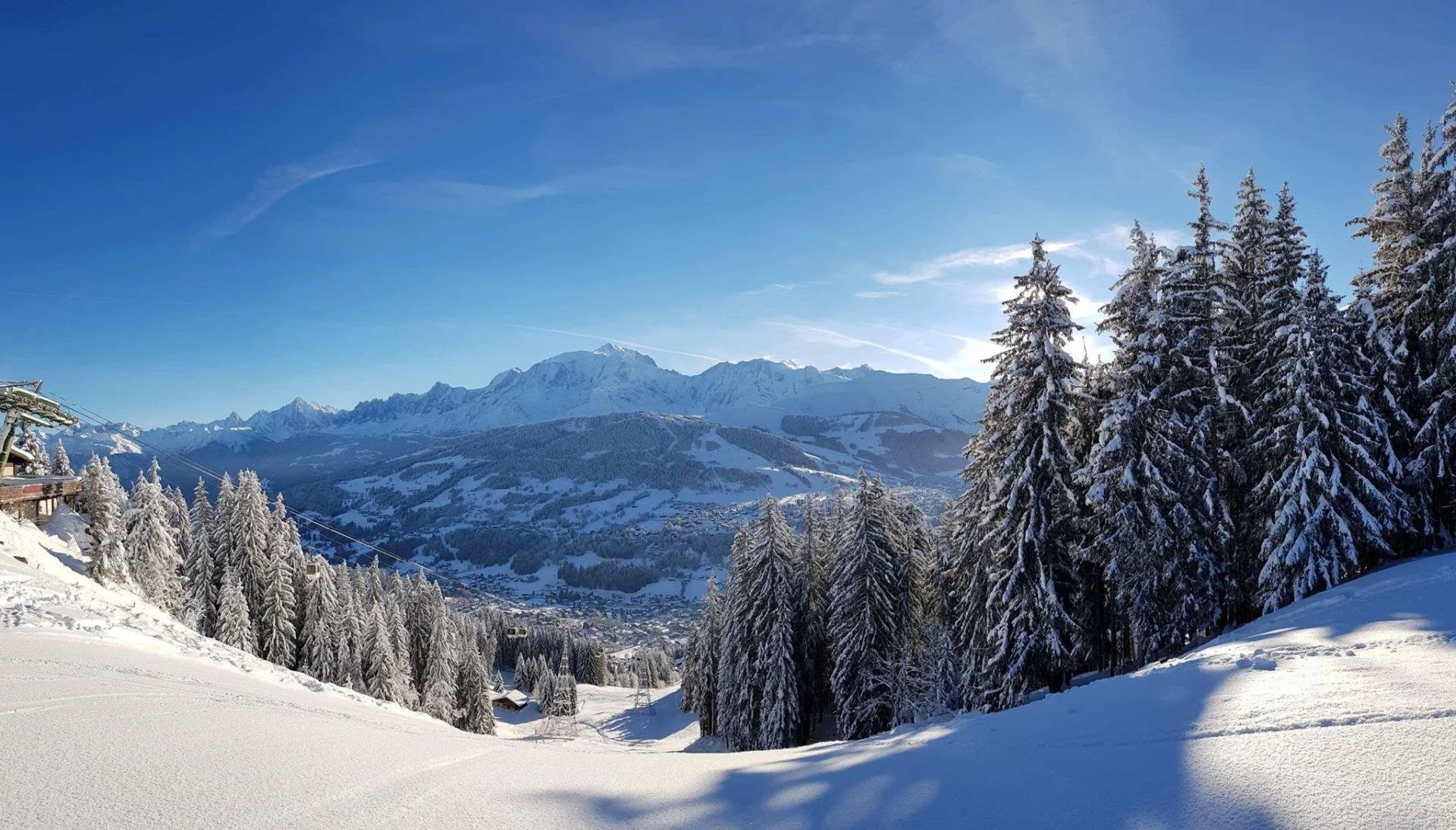 Snow-covered trees in Megeve, and mountains under a blue sky in a winter landscape