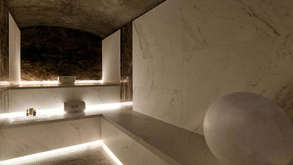 Interior of a modern spa room with marble surfaces, LED lighting, and a large stone ball.