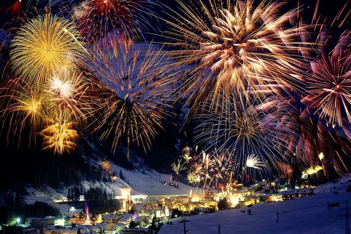 Fireworks lighting up the night sky over a snowy town.