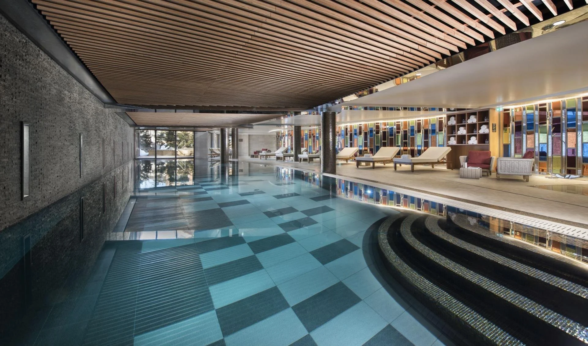 Indoor swimming pool with lounge chairs and colorful partition walls.