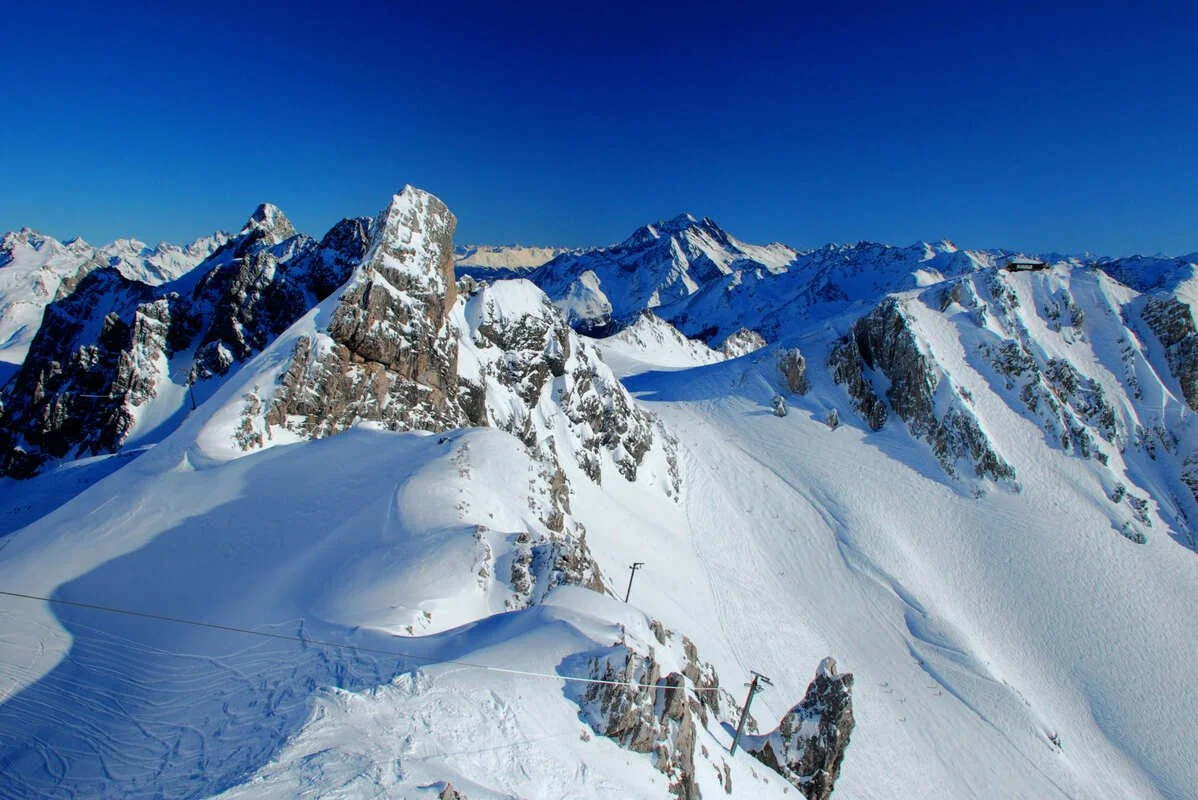 Snow-covered mountain peaks under a clear blue sky in a mountainous region.