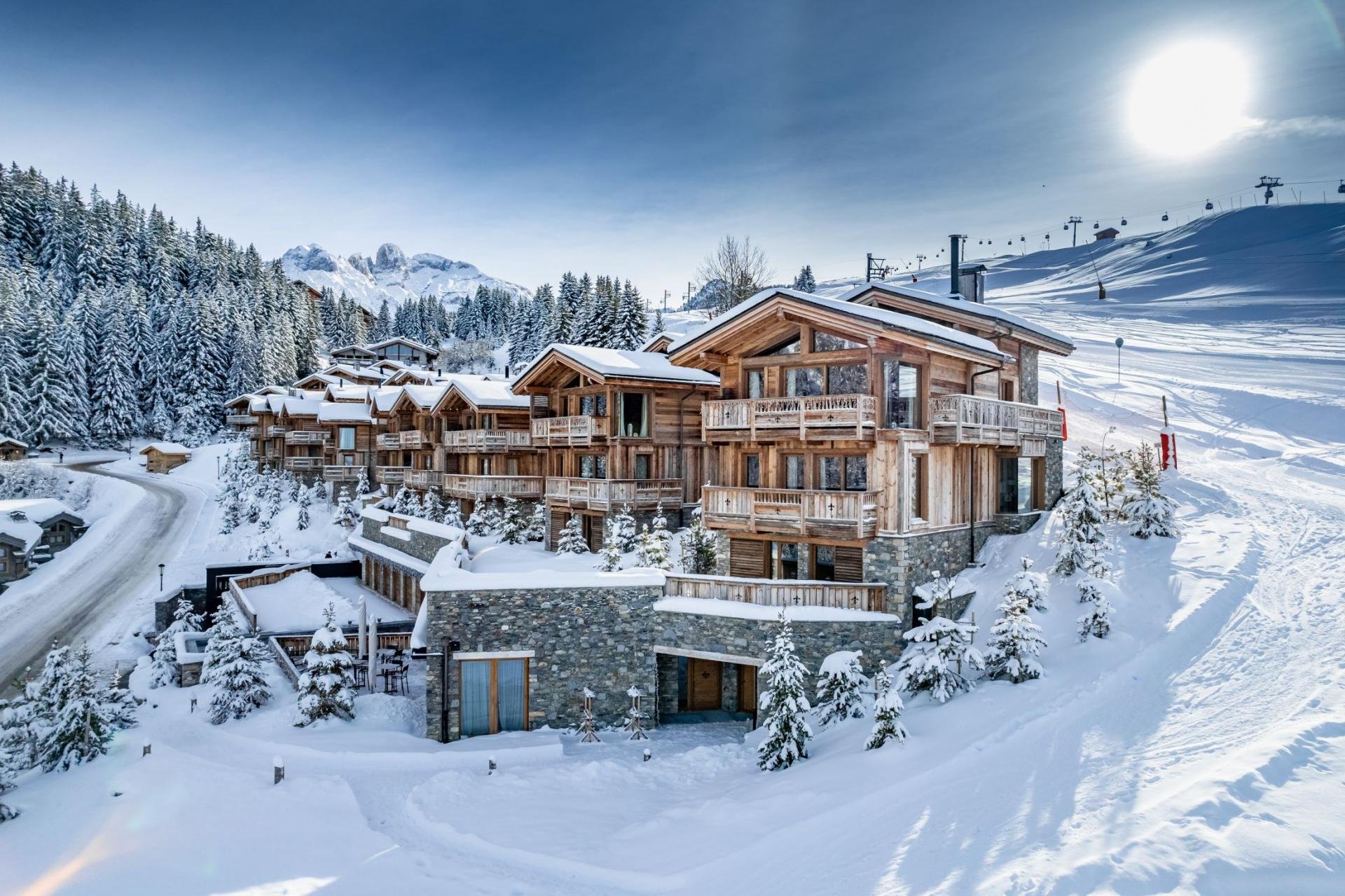Snow-covered mountain resort with wooden chalets and ski lifts on a bright, sunny winter day.