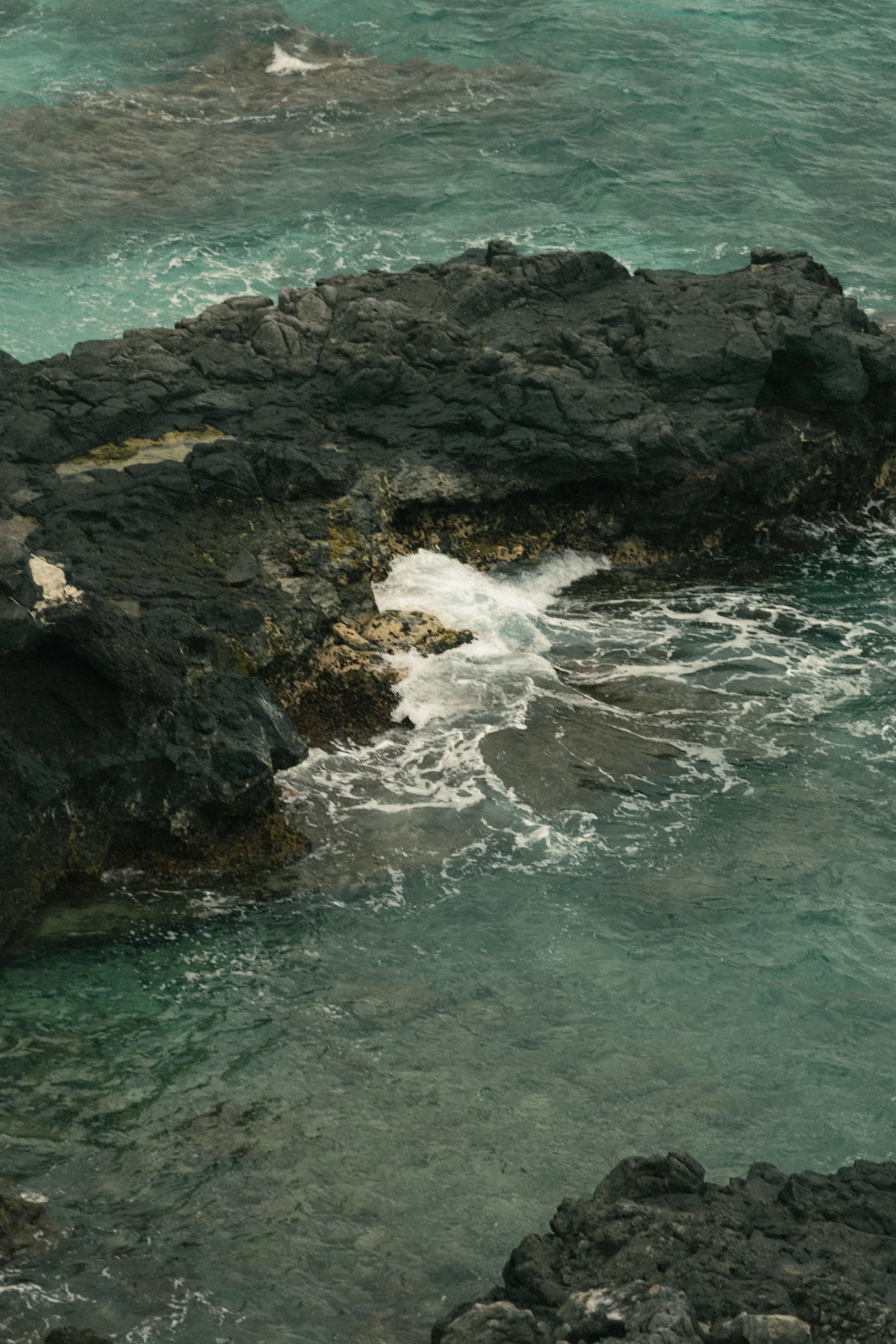 Ocean waves crashing against rocky shoreline with turbulent water.