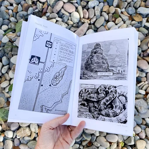 Open book with maps and illustrations resting on rocks.