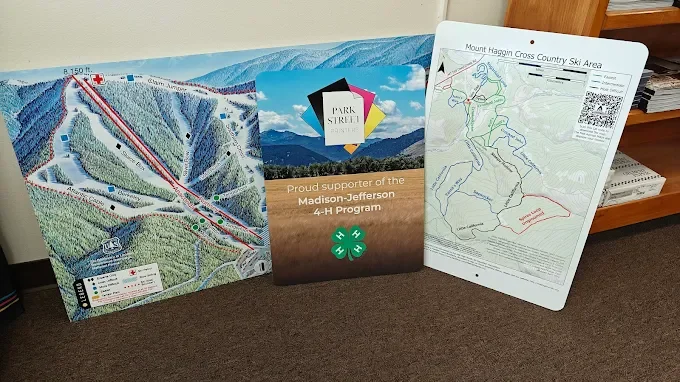 Three large informational maps and a brochure on the floor against a wall. The maps feature ski trails and area details, with the middle brochure displaying the logo for the Park Street Inn and a message supporting the Madison-Jefferson 4-H Program.