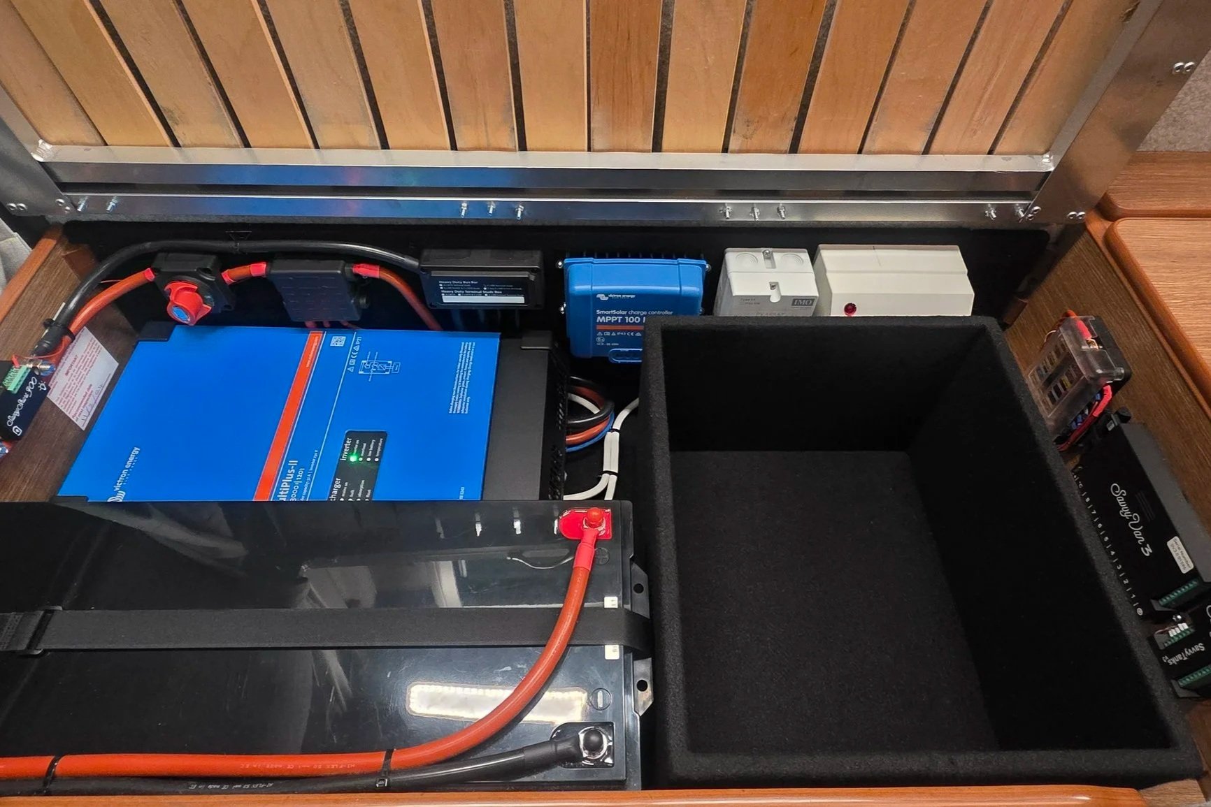 Boat battery and electrical system with blue inverter, charge controller, and storage compartments.