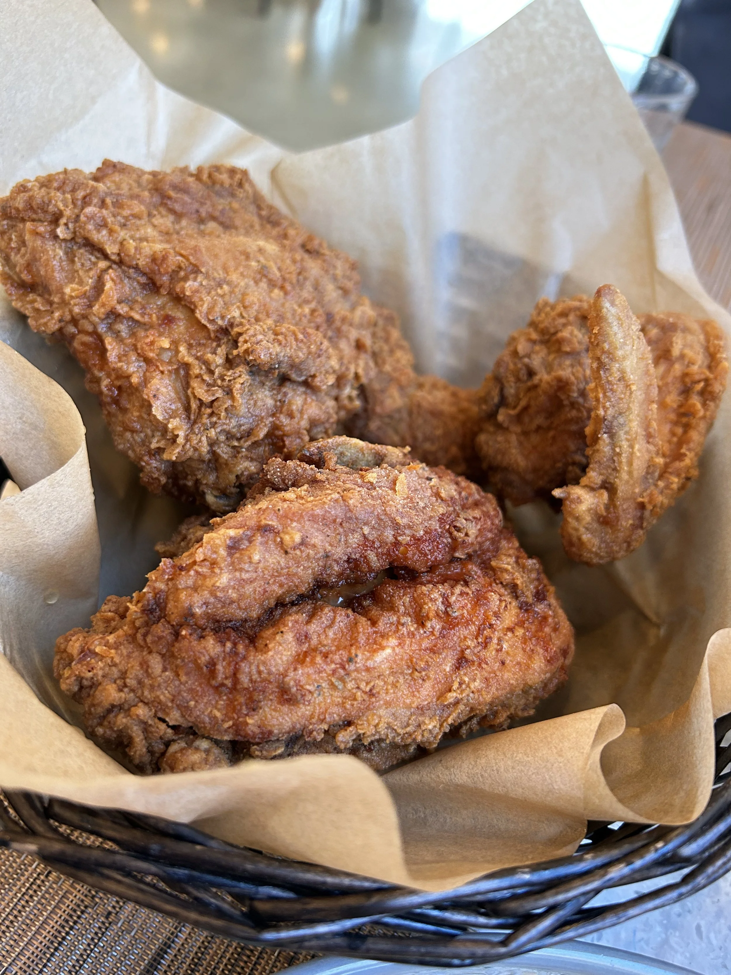 Basket of fried chicken, buttermilk biscuit, and blackened catfish over grits.