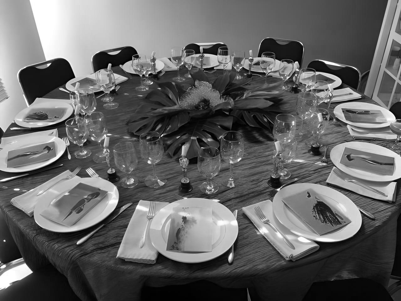 Elegant round dining table set with plates, utensils, glassware, and a central floral arrangement.
