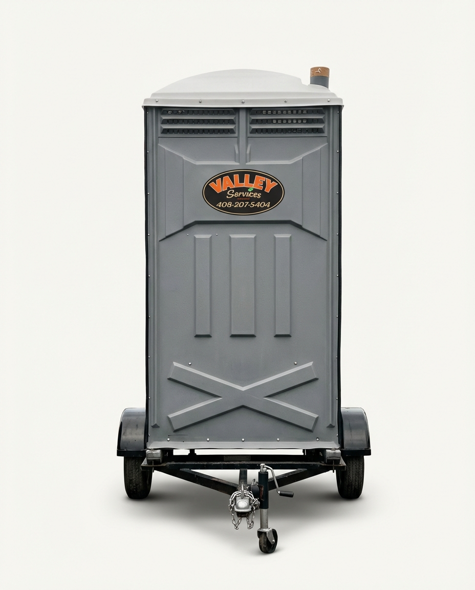 Portable toilets with "Valley Services" branding and a trailer in a sunny outdoor setting.