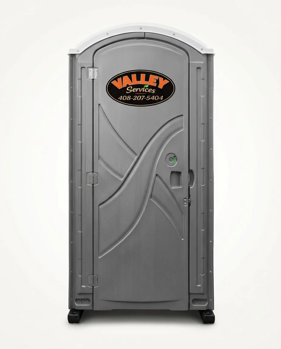 Gray portable toilet with a black and orange Valley Services logo and phone number on the door.