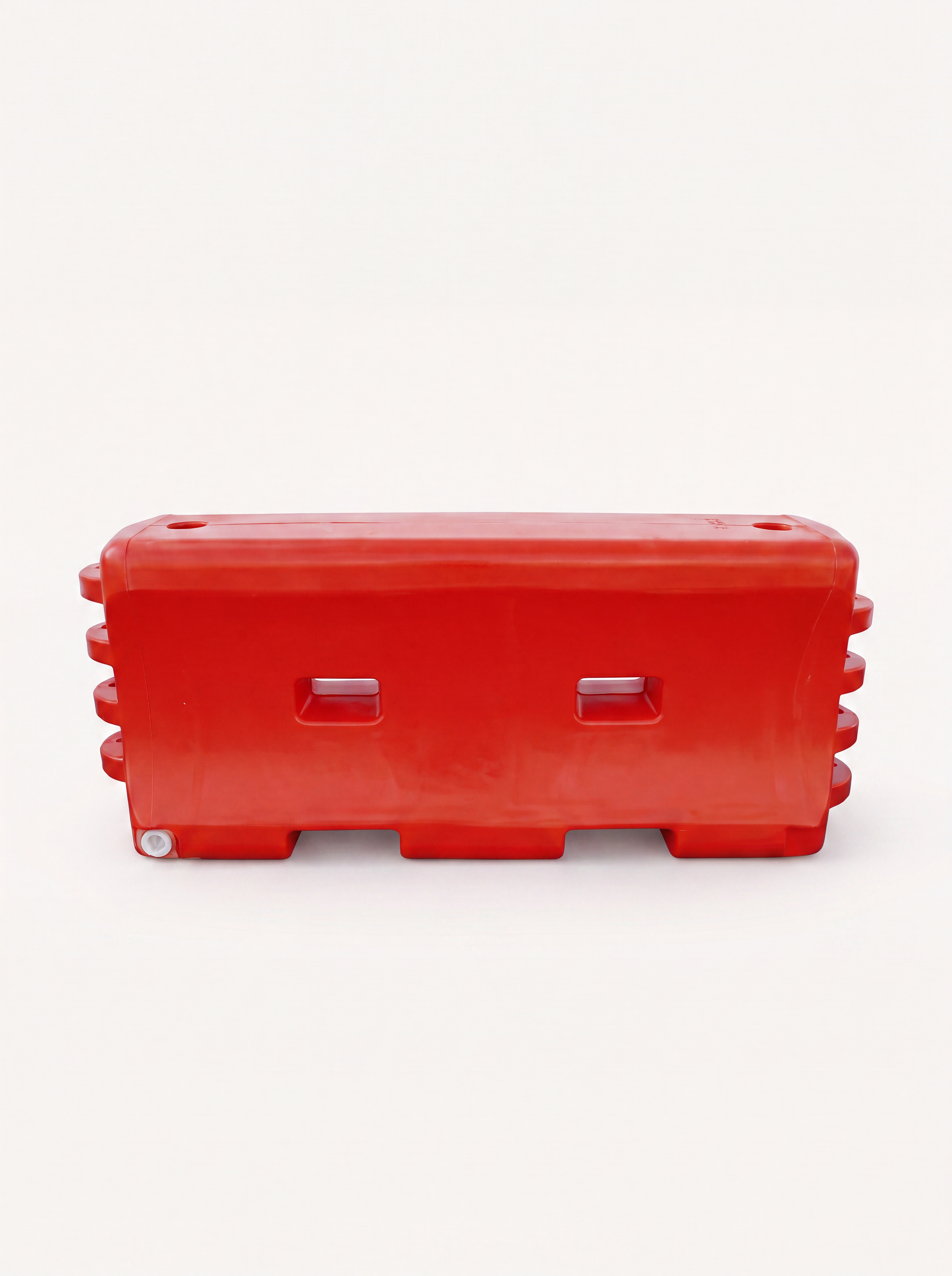 Red plastic safety barrier with multiple horizontal slots, placed against a plain light background.
