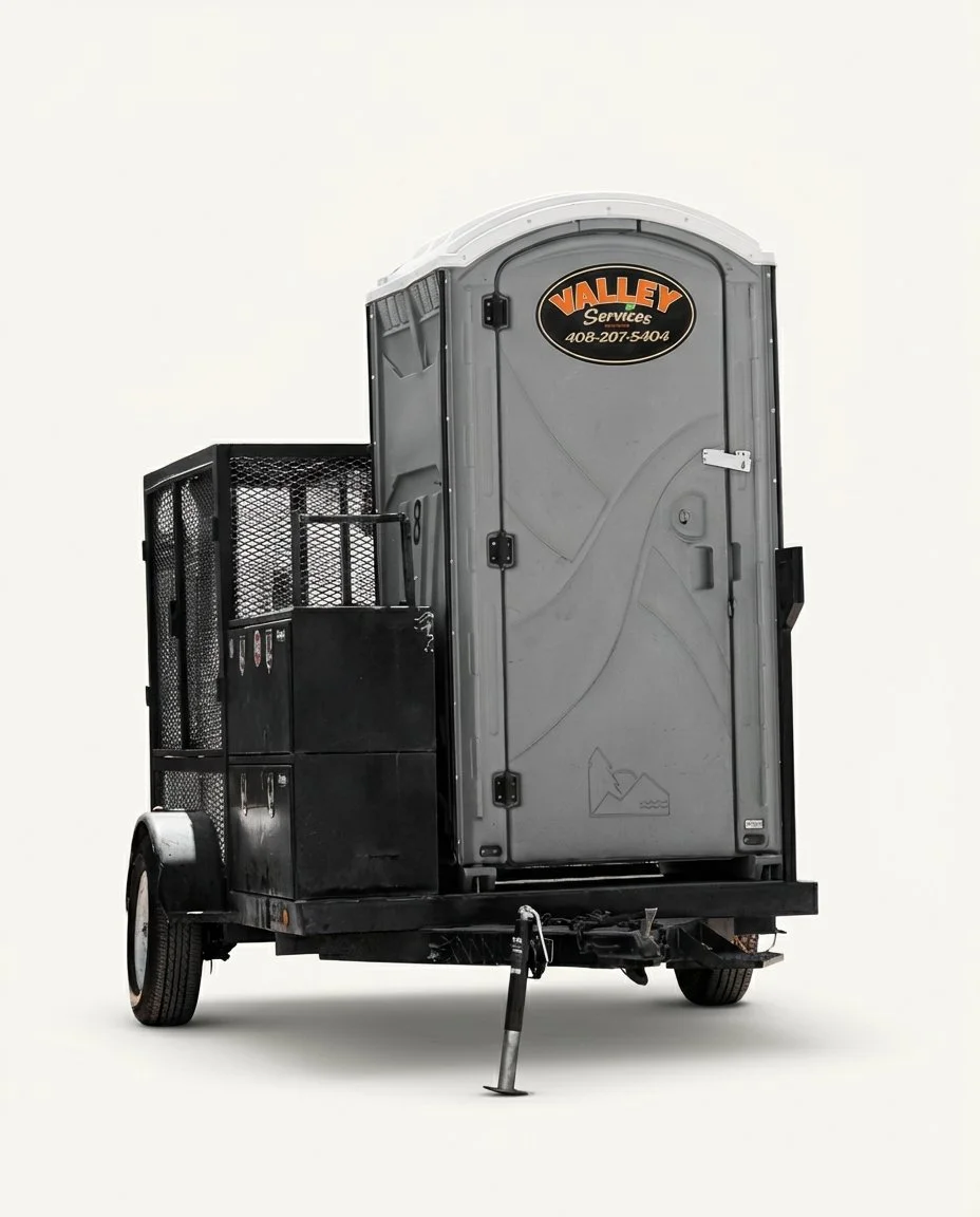 A portable toilet on a small trailer with a black storage box attached. The trailer is set against a plain, white background.