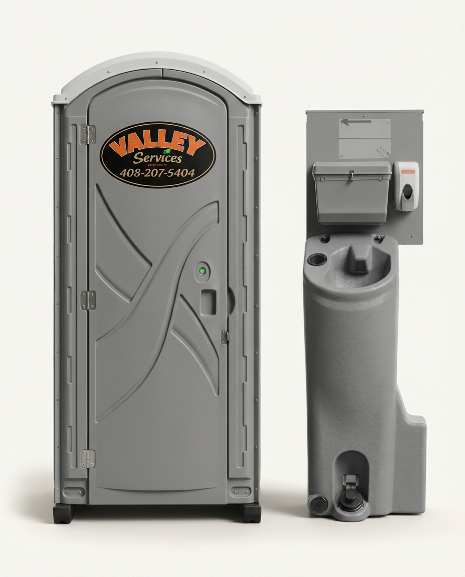 Portable toilet with a sign for Valley Services and a hand sanitizer dispenser attached to the wall next to it.