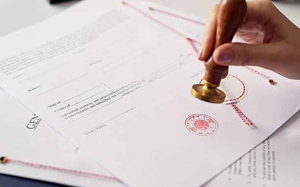 A person stamping a document with a seal.