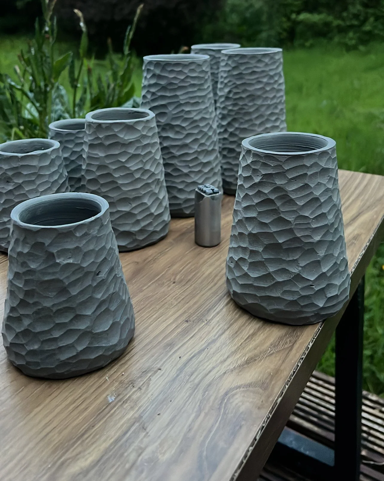 Collection of gray textured ceramic planters displayed on a wooden outdoor table