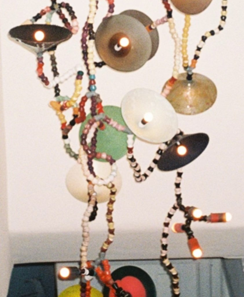 Colorful beaded light fixture with various round shapes and small bulbs.