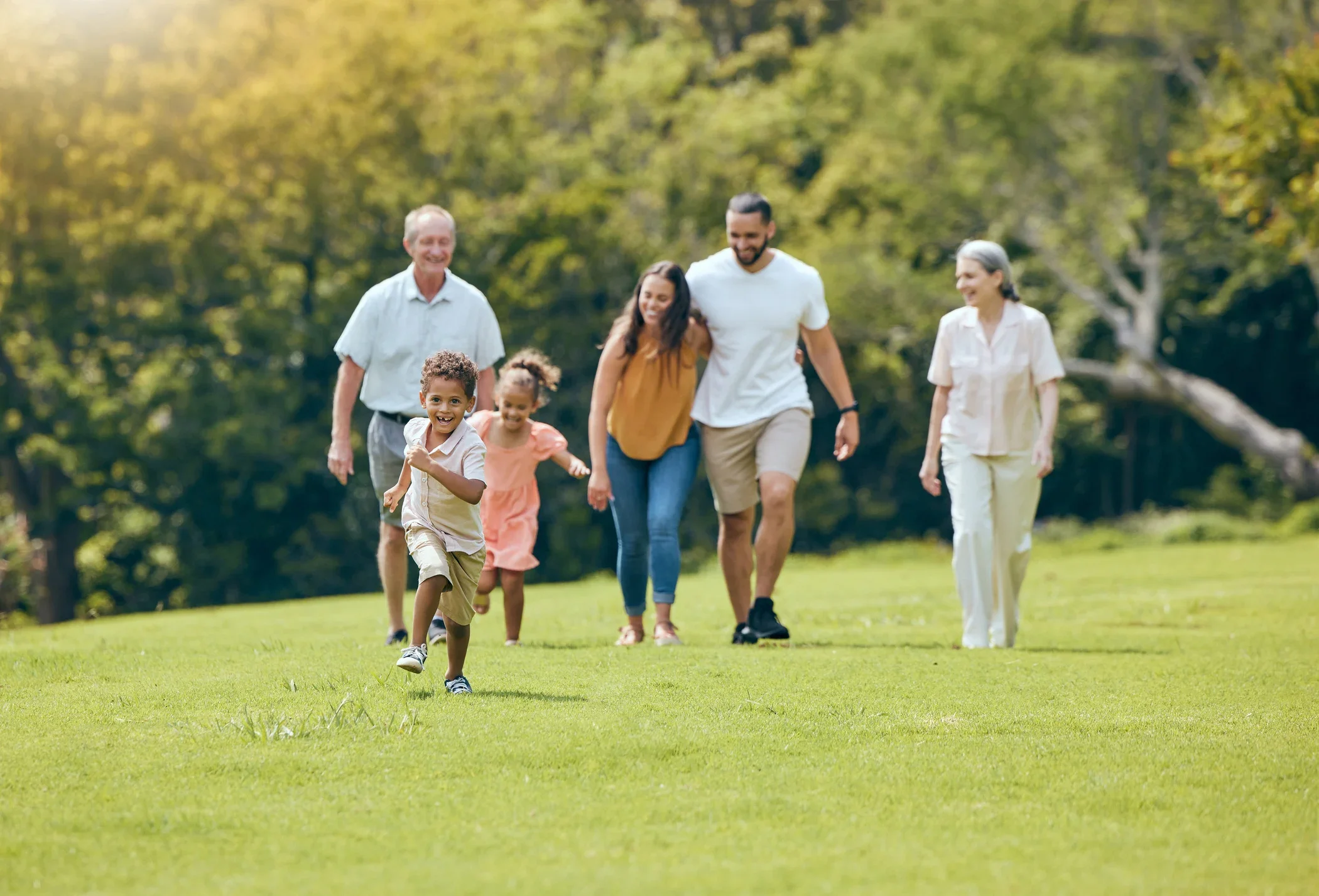 A multigenerational family enjoying a walk together in a park on a sunny day