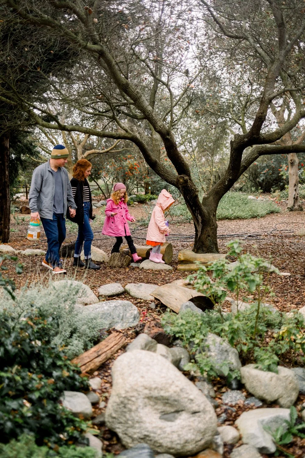 Family of four walking in Urban Forest, Huntington Beach California on a rainy day for a family mini session photoshoot.