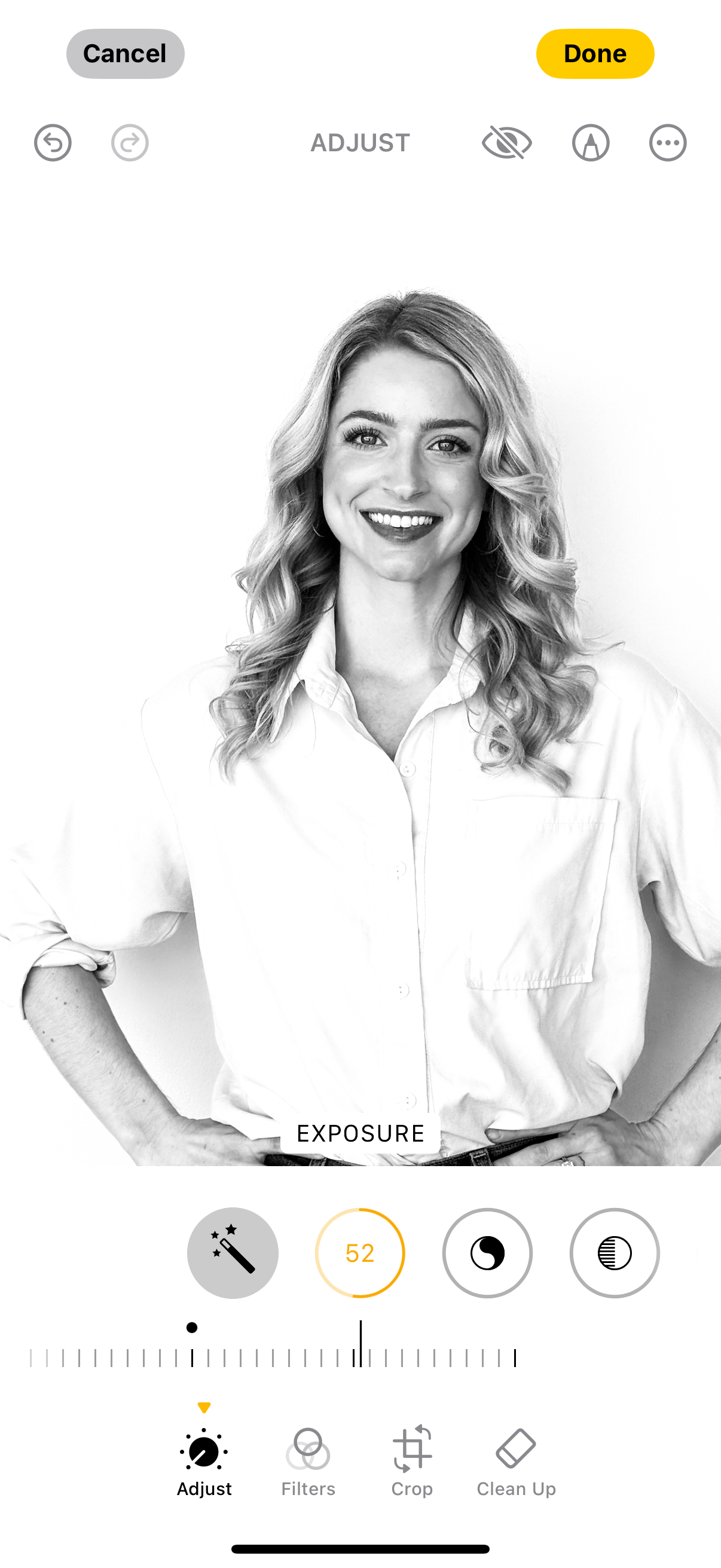 Black and white photo of a smiling woman with wavy hair, wearing a collared shirt, standing against a plain background.