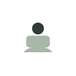 Simplified icon of a person sitting at a desk or table, shown as a dark circle for the head and a rounded rectangle for the body, with a flat surface in front.