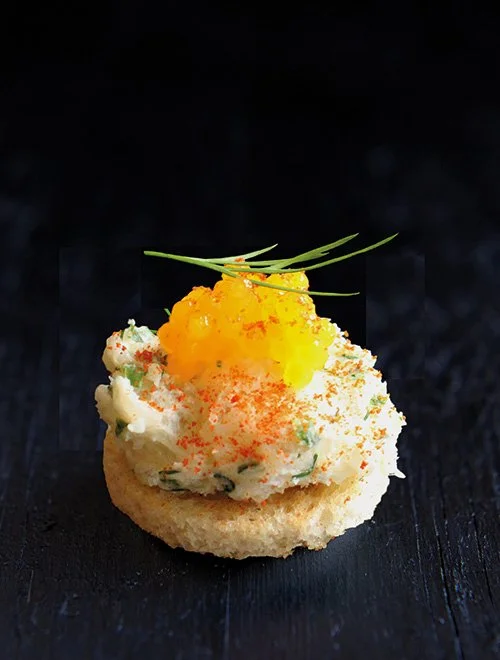 En kanapé med creme og orange kaviar på en kiks.