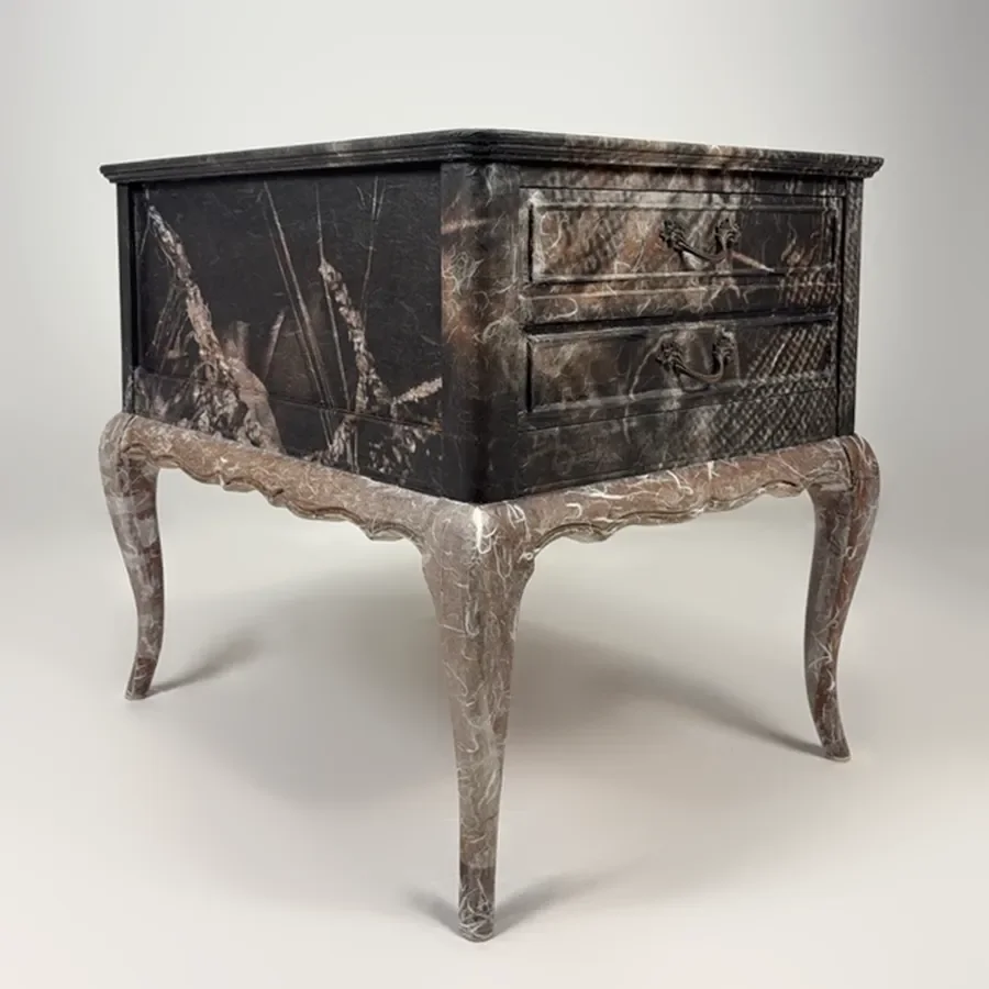 A vintage-style wooden nightstand or small table with a marble-like finish, featuring two drawers with ornate handles and curved legs.