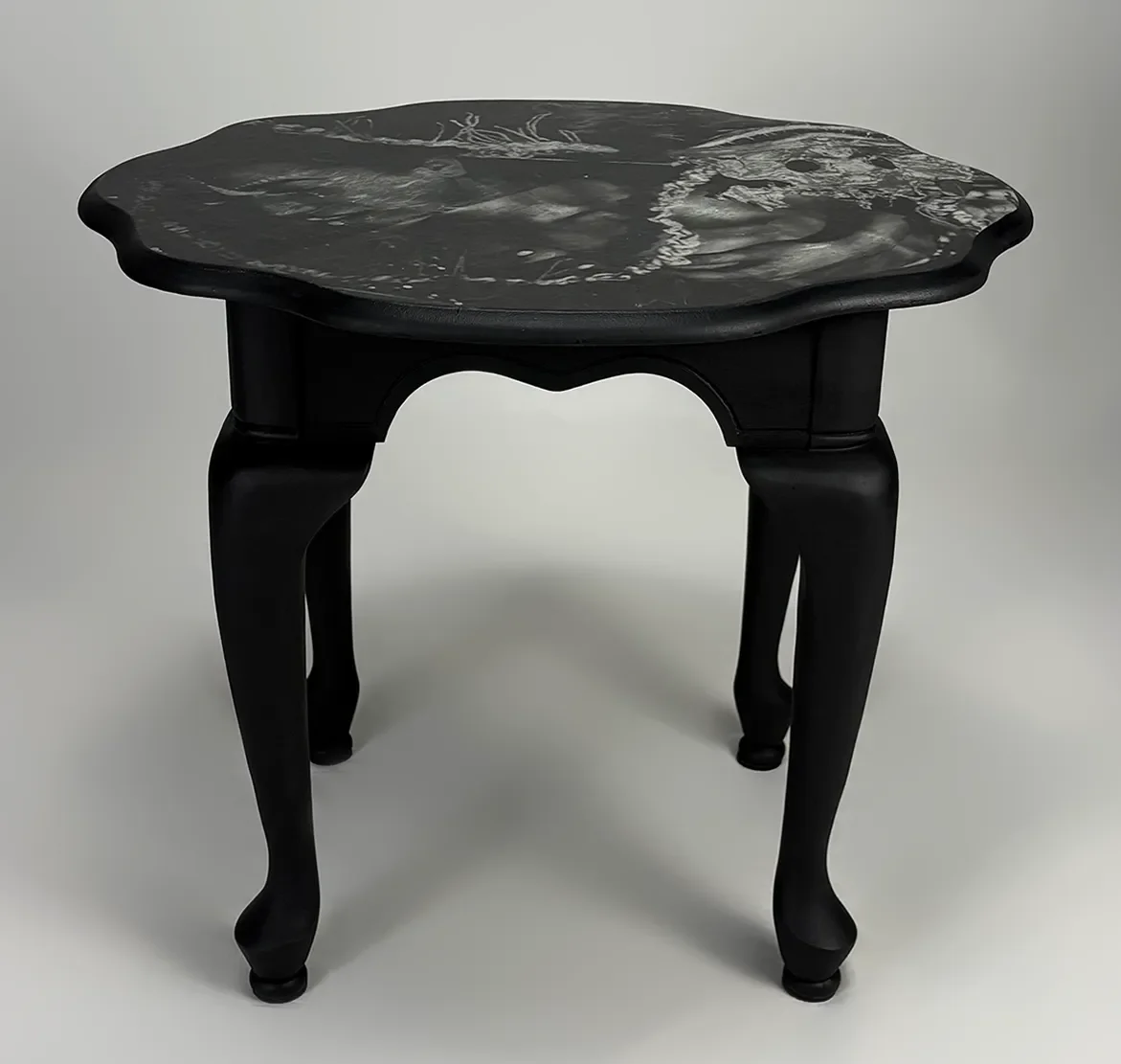 Black wooden table with a marble top that features a black and white design.