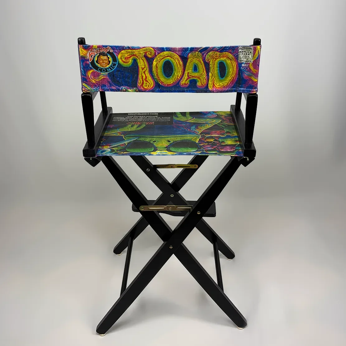 Colorful director's chair with psychedelic design and the word 'TOAD' on the backrest, set against a plain white background.