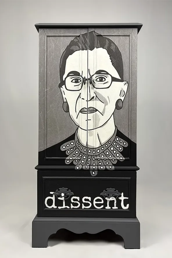 A black cabinet with a caricature of Ruth Bader Ginsburg's face on the upper part and the word 'dissent' written on the lower part, adorned with gear-like symbols.