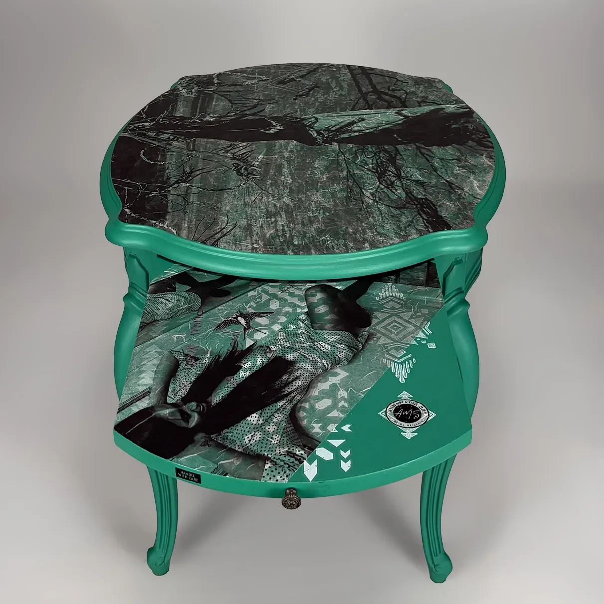 A turquoise-colored vintage side table with a black marble top featuring tree branches and leaves pattern.