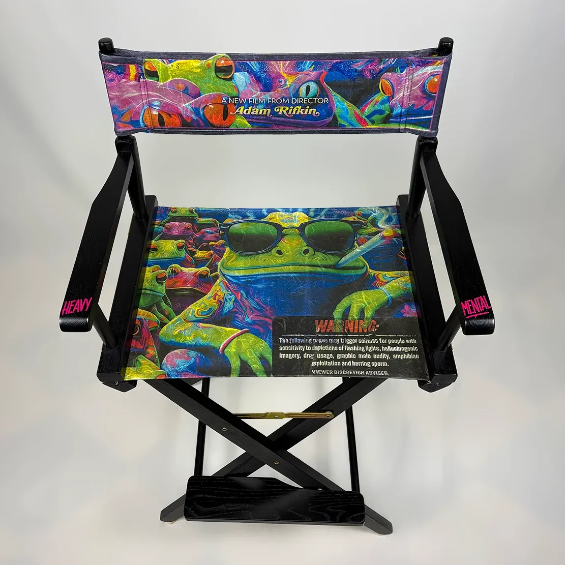 Colorful director's chair with vibrant frog and psychedelic patterns, sunglasses, and a warning label on the seat fabric.